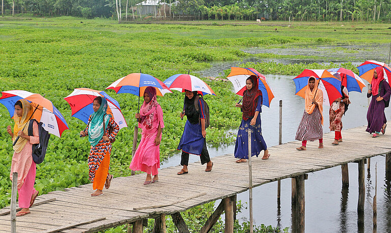 Frauen laufen auf einem Pfad durch Felder