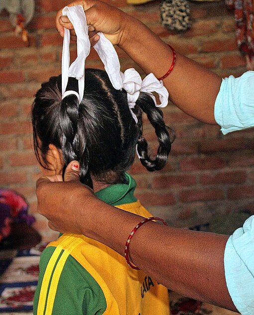Ram Kumari macht ihrer jüngsten Tochter die Haare zurecht Ein Frau frisiert ein Kind