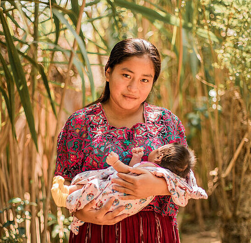 Sefora (18) aus Guatemala hält ihre drei Wochen alte Tochter im Arm Eine junge Frau hält ein Baby im Arm