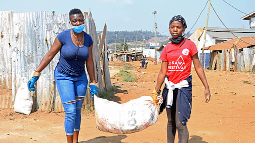 Pauline (links) und Quinter sorgen für mehr Hygiene in Kibera. Pauline und ihre Freundin tragen einen Sack.