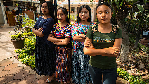 Vier Aktivistinnen in Guatemala machen sich in einem Plan-Projekt für die politische Beteiligung von jungen Frauen stark Vier junge Frauen stehen draußen unter Palmen. Sie haben die Arme vor der Brust verschränkt und schauen ernst in die Kamera
