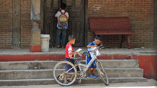 Zwei Kinder vor Treppen mit einem Fahrrad.