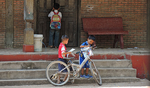 Zwei Kinder vor Treppen mit einem Fahrrad.