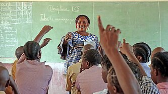 Eine Frau steht an einer Tafel vor einer Schulklasse