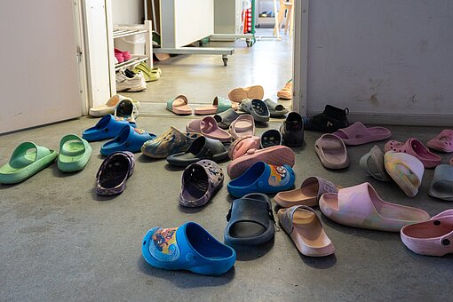 Vor einem Raum mit offener Tür stehen jede Menge Hausschlappen