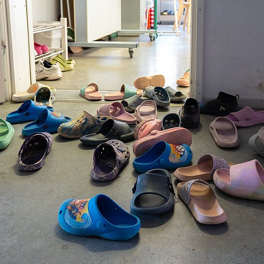 Vor einem Raum mit offener Tür stehen jede Menge Hausschlappen