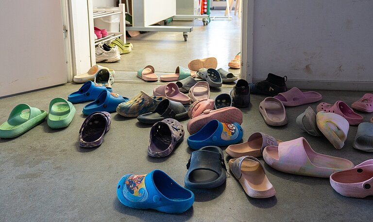 Vor einem Raum mit offener Tür stehen jede Menge Hausschlappen