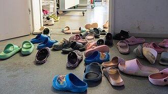 Vor einem Raum mit offener Tür stehen jede Menge Hausschlappen