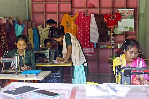 Aarati hat junge Frauen bei sich in die Lehre genommen und bringt ihnen das Fachwissen für Schneiderei bei Frauen in Nepal sitzen an Nähmaschinen
