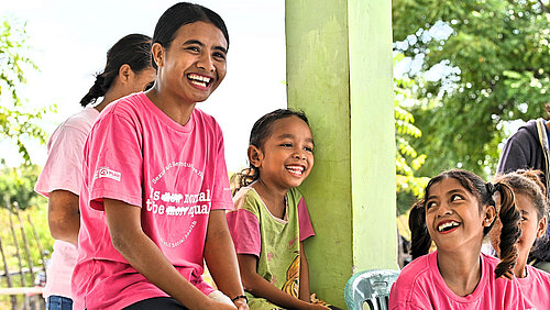 In Indonesien gibt es Workshops, vor allem für Mädchen und Frauen, damit sie sich besser vor Gewalt schützen können. Ein Mädchen im pinken Plan T-Shirt lacht in einer Gruppe mit anderen Mädchen