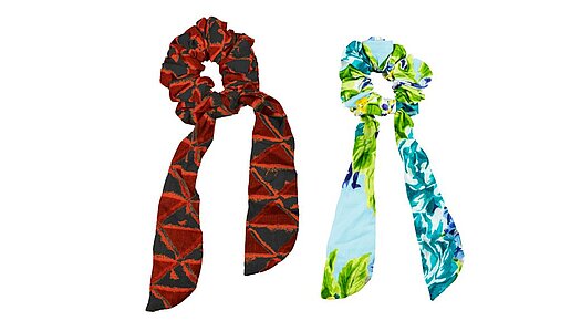  2er Scrunchie Set. An dem mit Stoff ummantelten Gummi hängen zwei Schleifenenden.