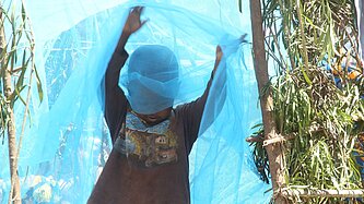 Junge in Ruanda spielt mit Moskitonetz