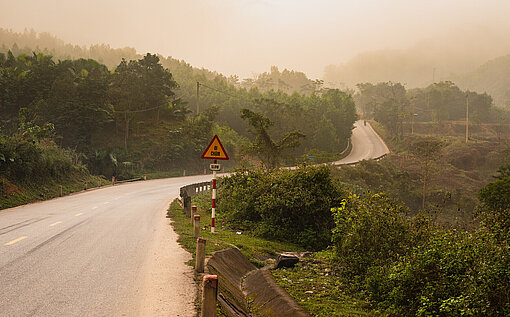 Auch in der Provinz Quang Binh in Zentral-Vietnam ist das Internet angekommen – und damit die Gefahr von Cyber-Mobbing und Missbrauch Im Morgennebel liegt eine einsame Landstraße in Vietnam.