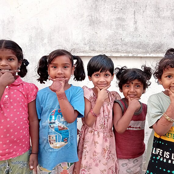 Kinder halten sich eine Hand ans Kinn und lächeln