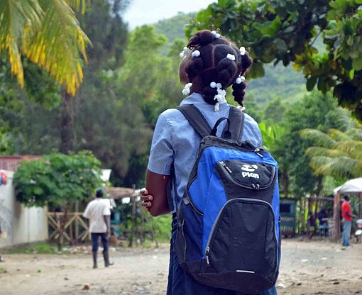 Ein Schulmädchen läuft durch ein Dorf