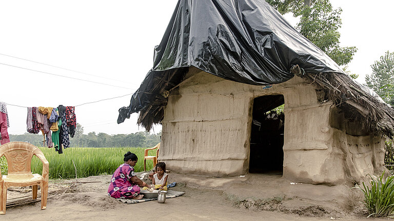 Bhumika und ihre Mutter sitzen vor ihrer Hütte.