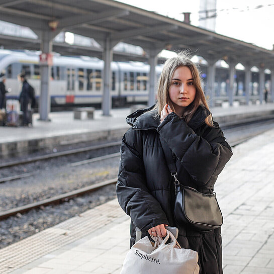 Eine junge Frau steht an einem Bahngleis