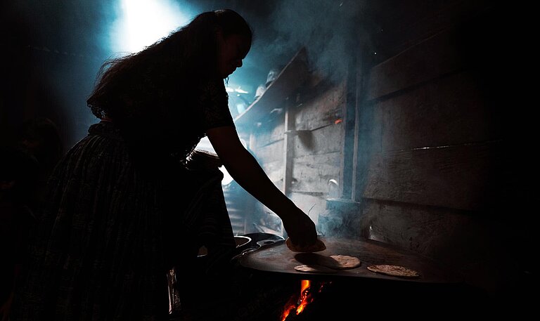 Eine Frau steht am Herd und backt Tortillas.