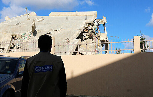 Ein Plan Mitarbeiter im Süden Libanons betrachtet ein Gebäude in Trümmern 