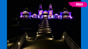 Ein pink angestrahltes Gebäude am Strand
