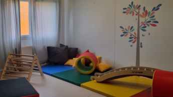 Ein bunt eingerichteter Raum für Kinder, mit Spielgeräten wie einer kleinen Kletterleiter.