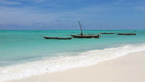 Sonnenseiten Sansibars: paradiesische Strände des tropischen Archipels. Strand, auf dem mit türkisem Meer liegen 4 Boote.
