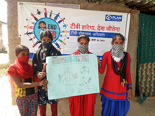 Kampagne gegen Tuberkulose in Indien Vier Mädchen mit Mundschutz halten ein Plakat hoch