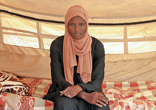 Weam (16) musste seit dem Ausbruch des Krieges in Sudan mehrfach fliehen Ein Mädchen sitzt in einem Zelt