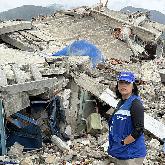 Eine Mitarbeiterin von Plan International steht vor einem eingebrochenen Gebäude in Venezuela