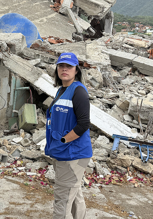 Eine Mitarbeiterin von Plan International steht vor einem eingebrochenen Gebäude in Venezuela