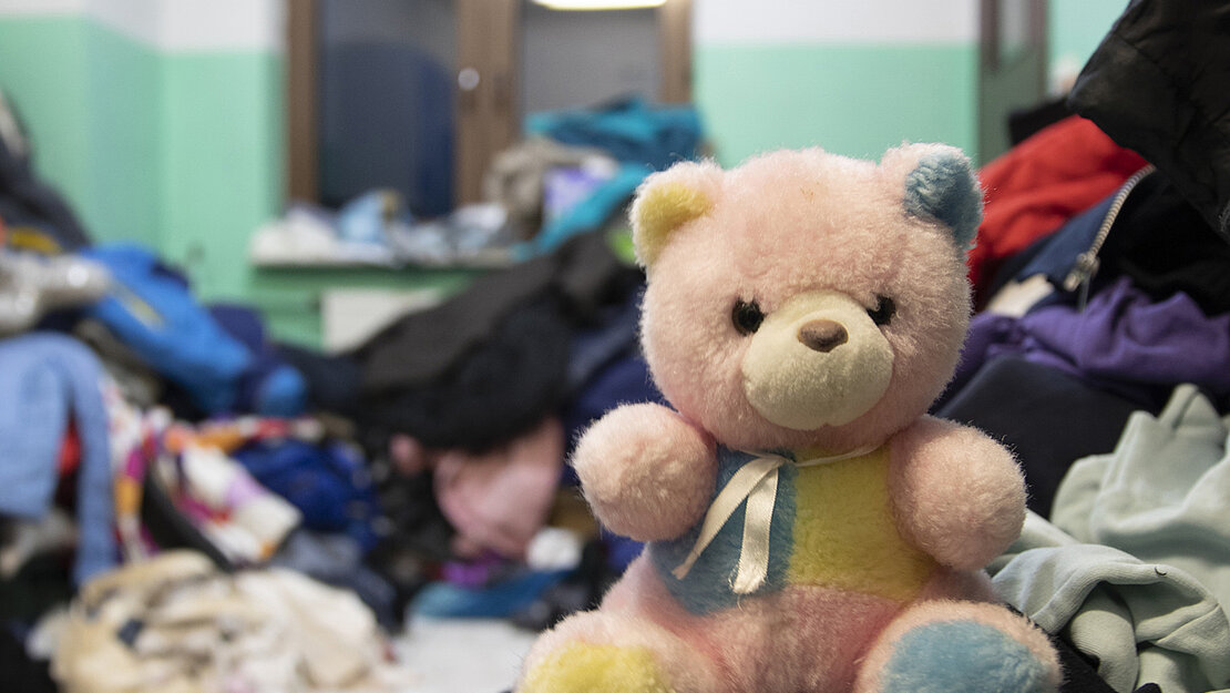 Menschen haben auch Anziehsachen und Spielzeug für die Menschen, die aus der Ukraine ankommen, gespendet. Ein Teddybär sitzt auf einem Haufen gespendeter Anziehsachen.