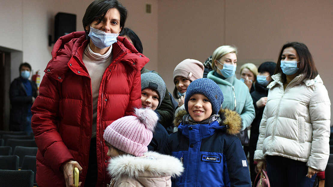 Kinder kommen mit ihren Müttern, um die Schulranzen abzuholen.