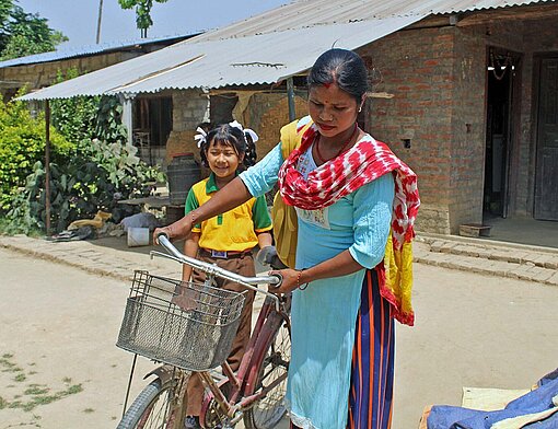 Mit dem Fahrrad bringt Ram Kumari ihre jüngste Tochter zur Schule Mutter und Kind auf Fahrrad