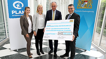 Symbolische Scheckübergabe in Höhe von 100.000€. V.l.n.r. Nicole Schmidt, Referentin Bayern und Baden-Württemberg (Plan), Pia Schmalhaus, Kinderschutzbeauftragte (Plan), Dr. Werner Bauch, Vorstandsvorsitzender (Plan) und Staatsminister Dr. Florian Herrmann. © Bayerische Staatskanzlei