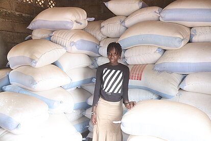 Ein Mädchen steht in einem Lager für Getreidesäcke