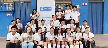 Junge Frauen posieren vor einem Plan-Plakat