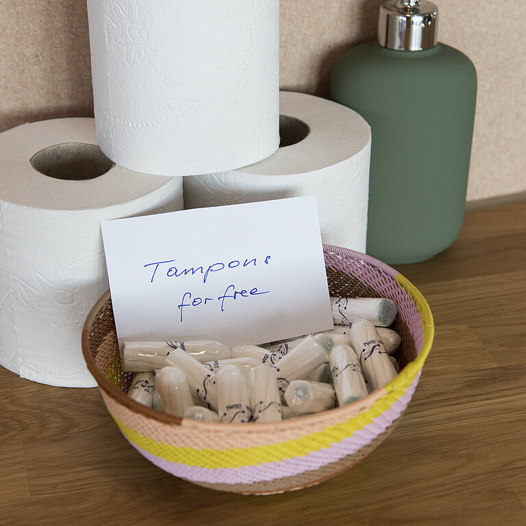 Drei Rollen Toilettenpapier und eine Schüssel mit Tampons