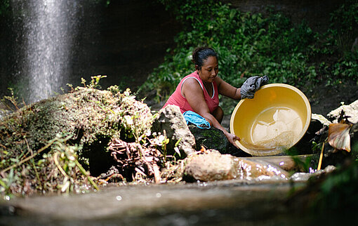 Mayra wäscht Geschirr in einem nahegelegenen Fluss in der Provinz Manabí.