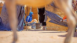 Eine Frau sitzt vor einer Strohhütte in Niger