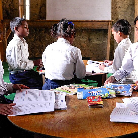 Vier Kinder sitzen an einem runden Tisch und lernen zusammen