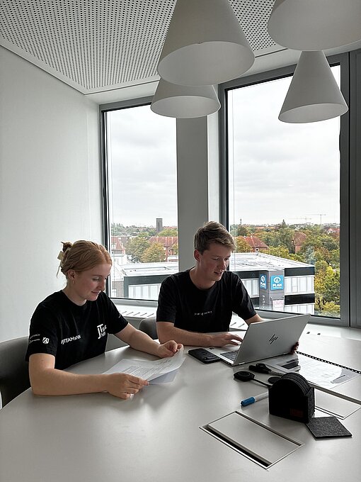 Eine junge Frau und ein junger Mann sitzen vor einem Laptop 