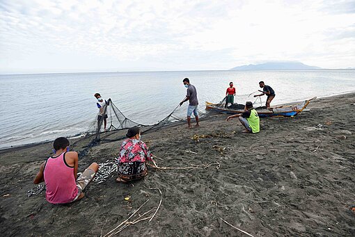 In der indonesischen Provinz Ost-Nusa Tenggara leben viele Familien vom Fischfang Menschen an einem Strand mit Netzen und Angelgeräten