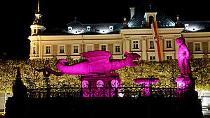 Der Lindwurm-Brunnen wird im Dunkeln Pink angestrahlt.