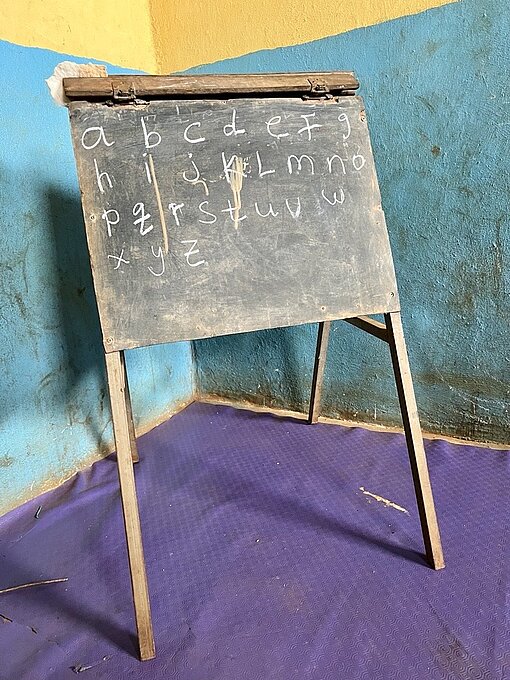 Eine kleine Schiefertafel mit dem Alphabet darauf steht in der Ecke eines Raumes