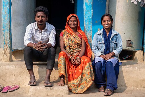 Mutter, Bruder und Ashiya sitzen vor ihrem Laden