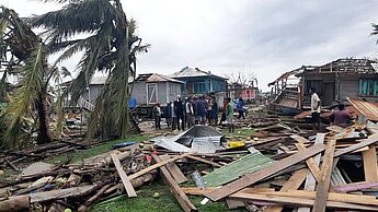 Puerto Cabezas, die wichtigste Küstenstadt im Norden Nicaraguas, wurde am schwersten von Hurrikan Eta getroffen. Bäume wurden entwurzelt, Häuser beschädigt und etliche Gemeinden sind ohne Stromversorgung. © Plan International Man sieht eine menge Holzplanken von abgedeckten Dächern auf dem Boden herumliegen, im Hintergrund umgewehte Palmen und zerstörte Häuserser