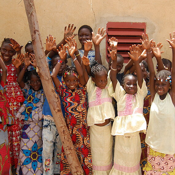 Kinder in bunter Kleidung strecken jubelnd die Arme in die Luft