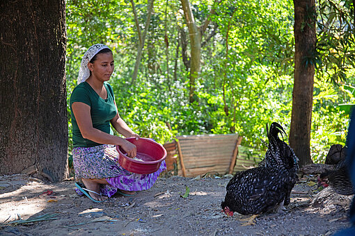 Eine Frau füttert Hühner