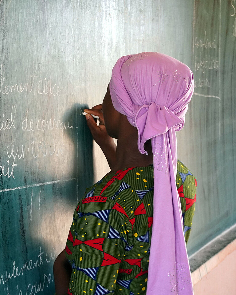 Eine junge Frau schreibt an eine Tafel.
