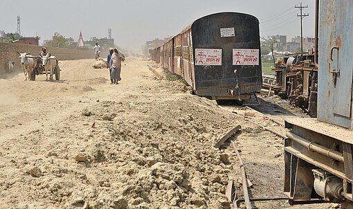 Von der früheren Bijalpura-Jaynagar-Railway ist nur eine sandige Naht geblieben. Sandige Straße neben einem alten Zug.